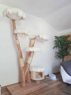 a cat tree in the corner of a room with white walls and wood flooring