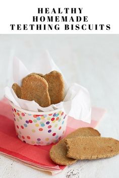 some cookies are in a paper cup on top of a pink napkin with the words healthy homemade teeth biscuits