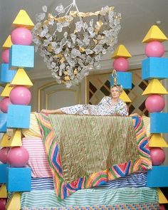 a woman laying on top of a bed covered in lots of colorful blocks and balls