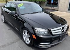 a black mercedes c - class parked in front of a building