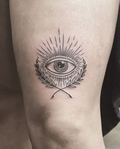 an all seeing eye tattoo on the right side of the leg, with a laurel around it