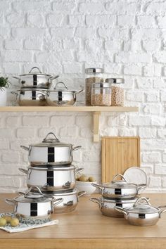 the pots and pans are sitting on the counter in front of the brick wall