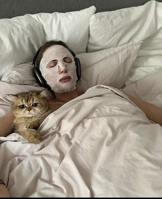 a woman laying in bed with a cat wearing a mask