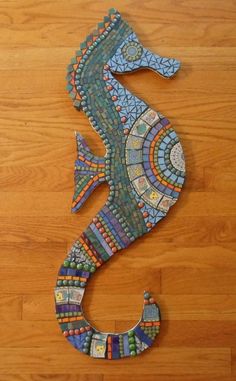 a seahorse made out of mosaic tiles on a wooden floor with a tile border