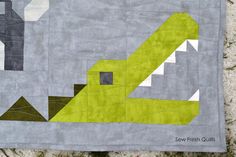 a green and gray patchwork quilt with an abstract design on the front, along with a white background