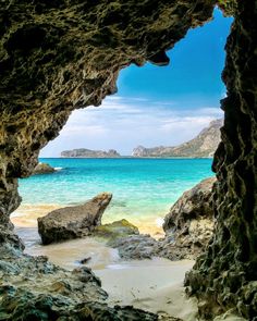 an ocean view from inside a cave on the beach