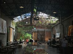 people are sitting at tables in an open area with plants growing on the walls and ceiling