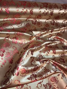 the fabric is very shiny and has pink flowers on it, as well as an intricate design