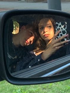 a man and woman are looking at their cell phones in the rear view mirror