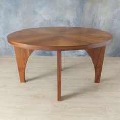 a round wooden table sitting on top of a hard wood floor covered in light colored paint