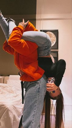 two people standing on their heads in front of a bed