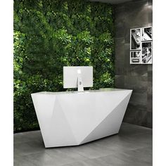 an apple computer sitting on top of a white counter in front of a green wall