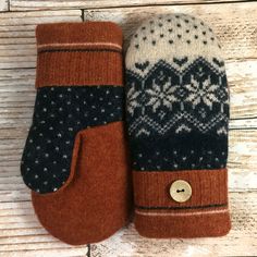 two mittens sitting on top of each other with buttons in the front and back