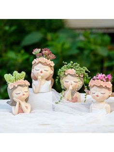 three little figurines sitting on top of a table with flowers in their hair