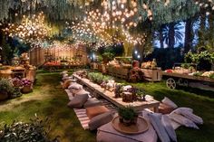 an outdoor dining area is lit up with string lights and hanging flowers above the tables