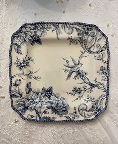 a blue and white plate sitting on top of a lace tablecloth covered table cloth