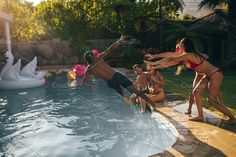 some people are in the pool and one person is jumping into the water while others look on