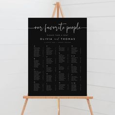 a black and white wedding seating chart on an easel with the names of guests