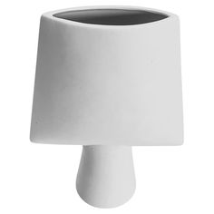 a white vase sitting on top of a table next to a black and white object