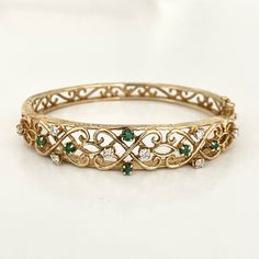 1950s Hinged Bangle Bracelet With Scrolling Open Work Motif Adorned With 8 Full Cut Diamonds And 6 Emeralds . The Bracelet Is In Mint Condition Without Dings Dents Nor Mechanical Issues. It Has Two Locking Systems And Both Work Well. The Bracelet Was Rarely Worn . It Is Stamped 14k . It Weighs 20.5 Grams. Elegant Multi-stone Bangle For Anniversary, Vintage Green Bangle For Wedding, Vintage Multi-stone Wedding Bracelets, Vintage Formal Bangle Hand Set, Vintage Wedding Bracelets With Multi-stone, Vintage Diamond Bangle Bracelet For Anniversary, Vintage Diamond Bangle For Wedding, Heirloom Multi-stone Bracelets For Formal Occasions, Hinged Bangle