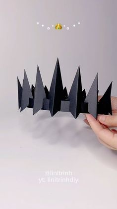 a hand is holding an origami forest