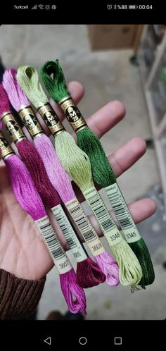 four skeins of different colors of yarn in the palm of someone's hand