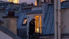 two people standing on top of a building next to each other in front of the eiffel tower