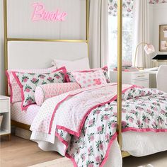 a bedroom with pink and white bedding, gold framed headboard and canopy bed