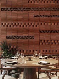 a wooden table with chairs and plates on it in front of a wall made out of bricks