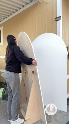 a woman leaning on a surfboard in front of a building with the door open