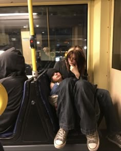 two people sitting on a subway train next to each other with their feet propped up