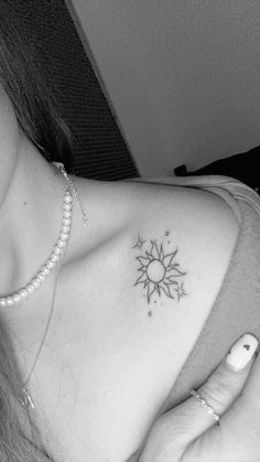 a black and white photo of a woman's chest with a sun tattoo on it