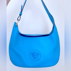 This Versace La Medusa Hobo Bag Is A Must-Have For Any Fashion-Savvy Woman. The Rectangular Shape And Pebbled Finish Give It A Unique And Stylish Look. The Magnetic Closure And Convertible Feature Add Convenience And Versatility. The Bag Is Made Of High-Quality Blue Leather With Gold Hardware, And It Comes With A Shoulder Strap Made Of The Same Leather With A Drop Of 9.5 Inches. The Bag Is Perfect For Travel, Casual Outings, Or Business Meetings. It Has A Medium Size With A Width Of 12 Inches, A Versace Blue, Versace Bags, Pink Fabric, Hobo Bag, Blue Leather, Magnetic Closure, Gold Hardware, Medium Size, Leather Handbags