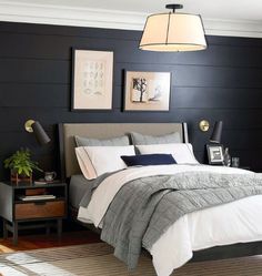 a bedroom with black walls, white bedding and two pictures on the wall above it