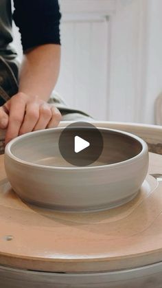 a person sitting at a table with a bowl on top of it and the video below