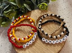 three beaded bracelets sitting on top of a wooden table next to a potted plant