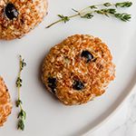 three cookies on a white plate with green sprigs