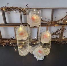 four clear vases with roses in them on a table