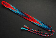 a red, blue and white rope with a tassel on the end sitting on a black surface