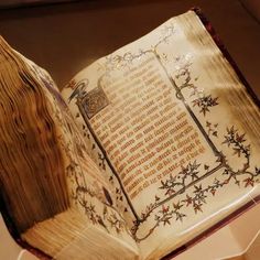 an open book on display in a glass case with floral designs and writing printed on the pages