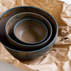 three brown bowls sitting on top of each other in front of some crumpled up paper