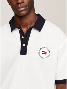 Tommy Hilfiger men's polo. A signature take on a preppy sports wardrobe classic, our pique polo features our iconic flag on the back. A winning mix of performance and style, Hilfiger Team pieces bring classic, American cool to the field, the court and beyond.  Material: 72% Transitional Cotton ,  In-conversion, 28% Polyesther Pes. Classic Polo Shirt With Ribbed Collar For Streetwear, Classic Polo Shirt With Signature Stripes, Classic Collared Polo Shirt With Signature Stripes, White Collared Polo Shirt With Signature Stripes, Classic Polo Shirt With Embroidered Logo For Streetwear, White Polo Shirt For College, Classic Polo Shirt With Logo Detail, White Sporty Polo Shirt With Embroidered Logo, Classic Collared Polo Shirt With Logo Detail