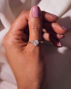 a woman's hand holding a diamond ring