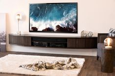 a flat screen tv sitting on top of a wooden entertainment center in a living room