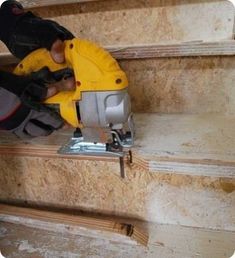 a person using a circular saw to cut plywood planks on the stairs in their home