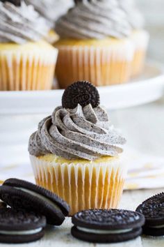 cupcakes with oreo cookies and frosting on a plate next to them