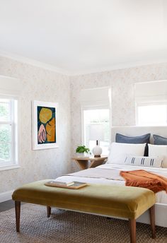 a bedroom with a large bed, two windows and a painting on the wall behind it