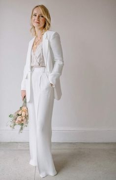 a woman in a white suit holding a bouquet