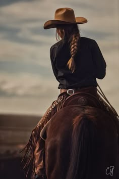 a woman wearing a cowboy hat is sitting on a horse