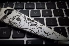 a knife sitting on top of a computer keyboard with skulls and bones painted on it